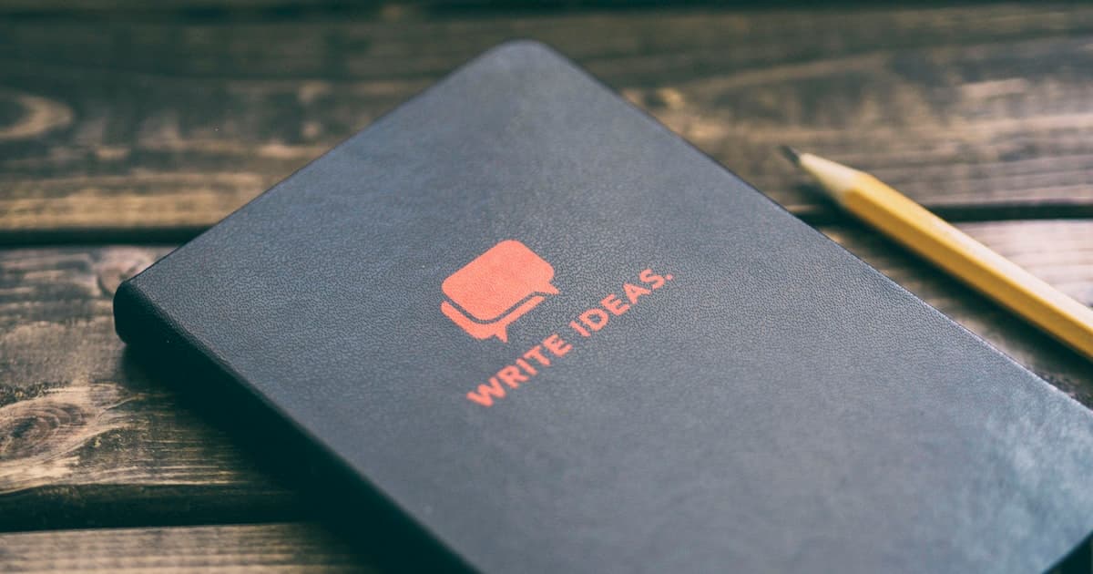Un carnet de notes fermé et un crayon sur une table en bois